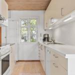 Küche mit Holzboden, Fenster und weißen Schränken