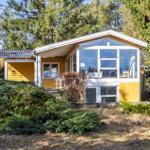 Ein gelbes Haus mit großem Glasbereich und Terrasse im Wald