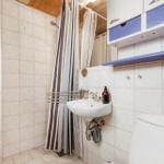 Badezimmer mit Waschbecken, Dusche und Toilette. Weiße Fliesen und Holzdecke.