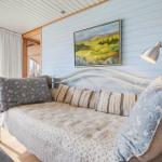 Ein Bett mit Kissen und Decke an einer blauen Wand mit Gemälde und Stehlampe.