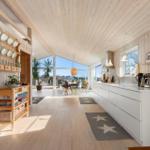 Küche mit weißem Schrank und Holzdecke. Blick auf Essbereich mit Tisch und Stühlen.