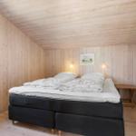 Schlafzimmer mit Holzwand, Bett und Kleiderschrank