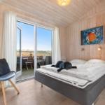 Schlafzimmer mit Bett, Stuhl und Balkonansicht.