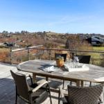 Terrasse mit Tisch und Stühlen, Blick auf Hügellandschaft mit Häusern.