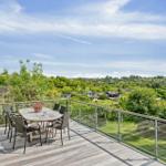 Terrasse mit Tisch und Stühlen, Blick auf grüne Landschaft und Häuser.