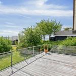 Terrasse mit Glasgeländer und Blick auf grüne Landschaft und Haus.