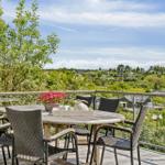 Terrasse mit Tisch und Stühlen, Blick auf grüne Landschaft.