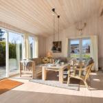 Wohnraum mit Holzdecke, Kamin und Glasfront zur Terrasse.