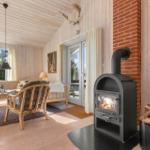 Wohnzimmer mit Kaminofen, Holzdielen und Sitzgelegenheiten.
