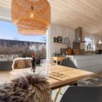 Essbereich mit Holztisch, Stühlen und Blick auf Balkon. Küche mit Arbeitsplatte und Küchengeräten.
