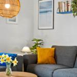 Grauer Sofa mit blauen und gelben Kissen, Wandbild und Lampe