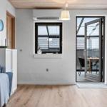 Wohnraum mit Sofa, Fenster und Glastür zum Balkon.
