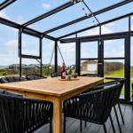Terrassenbereich mit Tisch und Stühlen, Blick auf Grünfläche und Himmel.