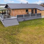 Haus mit Terrasse, Grill und Sitzgelegenheit im Freien.