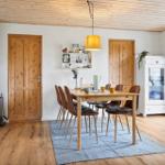 Esszimmer mit Holztisch, Stühlen und Kaminofen.