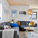 Wohnzimmer mit grauem Sofa, runden Tisch und Holzdecke.