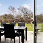 Terrasse mit Tisch und Stühlen, Blick auf Garten und Bäume.
