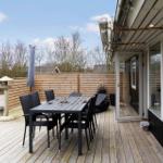Terrasse mit Tisch und Stühlen, Holzdecke, Garten und Schutzzaun.
