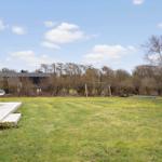 Großer Garten mit Spielplatz, Holzterrasse und Blick auf Wald.