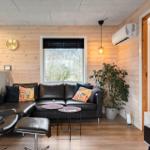 Wohnzimmer mit Ledersofa, Pflanzen und Fernseher.