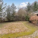Haus mit Terrasse, Garten und Wald im Hintergrund.