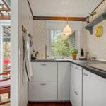 Küche mit weißen Schränken, dunkler Arbeitsplatte und Fensterblick auf Garten.