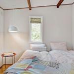 Schlafzimmer mit Bett, Fenster und Wandbild mit Flamingo.