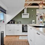 Küche mit weißer Einbauküche, Holzboden und grüner Wand