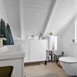 Badezimmer mit Waschbecken, Toilette und Heizung unter schrägem Dach