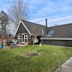 Schwarzes Haus mit Garten und Terrasse. Holzverkleidung und Dach aus Metall.