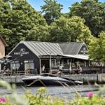 Fiskehuset Restaurant am Wasser mit Booten und Bäumen im Hintergrund.