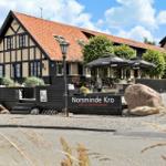 Norsminde Kro mit Terrasse, Sitzgelegenheiten und Steinmauer im Vordergrund.