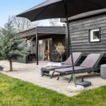 Terrasse mit Liegestühlen, Sonnenschirm und Gartenhaus mit Holzfassade.