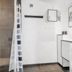Badezimmer mit Dusche, Waschmaschine und Spiegelschrank.