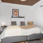 Schlafzimmer mit Bett, Wandbild und Holzdecke.