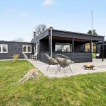 Moderne Villa mit Terrasse, Sitzgelegenheiten und Feuerkorb im Garten.