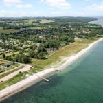 Strandort mit Ferienhäusern und Grünflächen entlang der Küste.