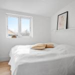 Schlafzimmer mit Bett, Fenster und Wandbildern.