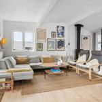 Wohnzimmer mit Sofa, Sesseln, Kamin und Wandbildern.