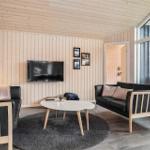 Wohnzimmer mit Holzwänden, zwei schwarzen Sofas und runden Tisch.