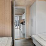 Zwei Betten in einem Raum mit Holzwand. Durchgang zur Küche und Terrasse.