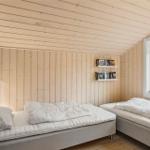 Zwei Betten mit weißen Bettwäsche in einem holzvertäfelten Zimmer mit Fenster.
