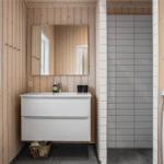 Badezimmer mit Waschbecken, Spiegel, Dusche und Waschmaschine.