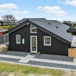 Schwarzes Holzhaus mit Terrasse und Garten. Modernes Design mit weißen Fenstern.