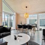Wohn- und Essbereich mit schwarzen Sofas, weißem Tisch und Holzdecke.