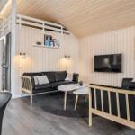 Wohnzimmer mit Sofa, Sessel und Fernseher an Holzwand. Obergeschoss mit Schlafplatz.