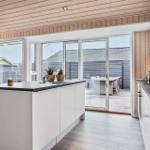 Küche mit Insel, Glasfront zum Balkon und Holzdecke.