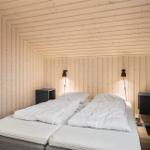 Schlafzimmer mit zwei Betten, Holzwand und Nachttischen