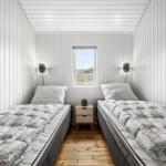 Zwei Betten mit gemusterten Bettdecken, Holzboden und Fenster im Schlafzimmer.