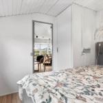 Schlafzimmer mit Bett, Fenster und Blick in Wohnbereich.